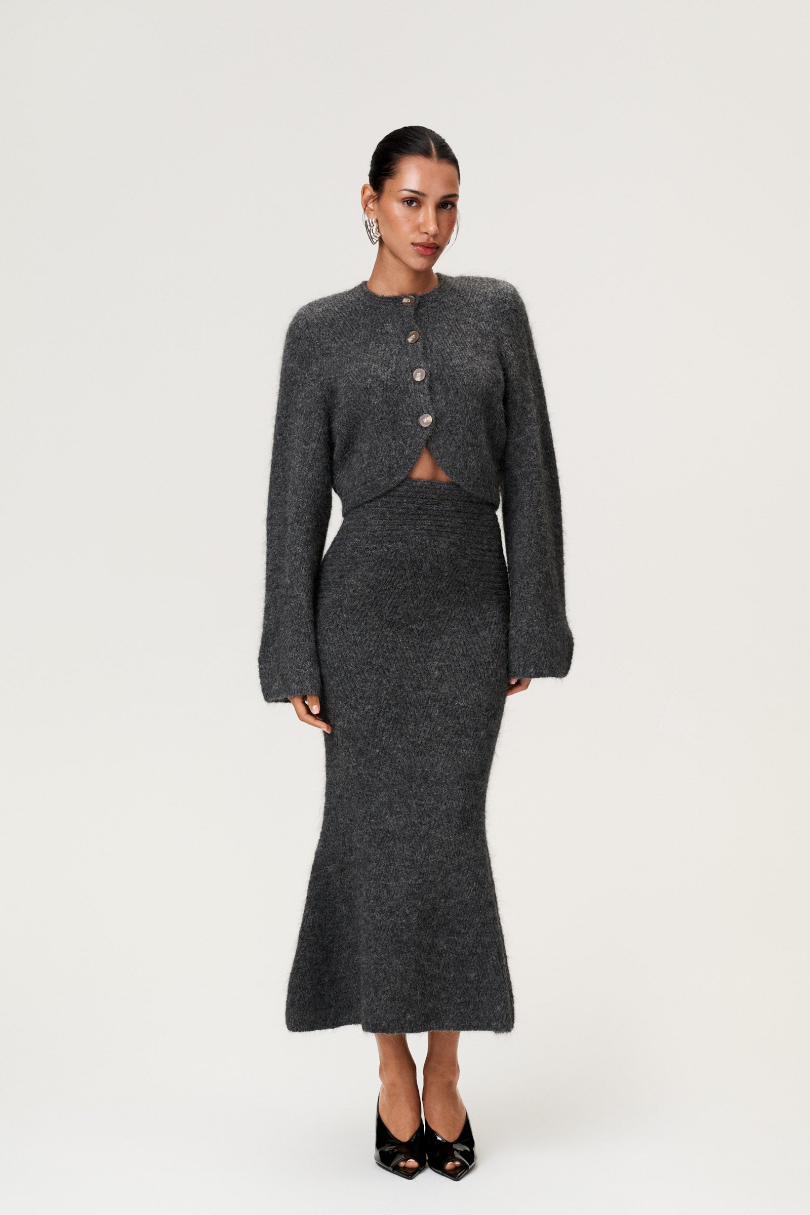 Woman wearing a Cessole cardigan and Cessole midi skirt in a gray textured knit, Adoore signature buttons, wide sleeves and cropped fit. image