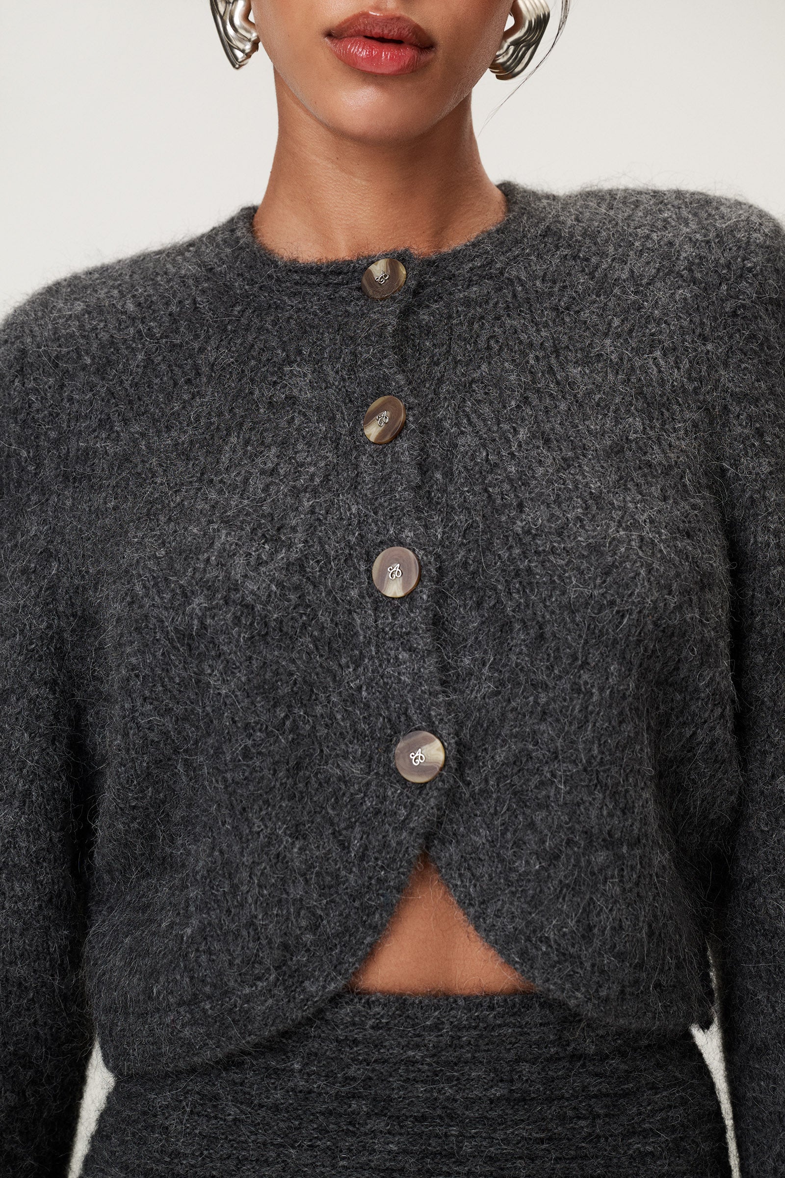 Woman wearing a Cessole cardigan in a gray textured knit, Adoore signature buttons, wide sleeves and cropped fit. image