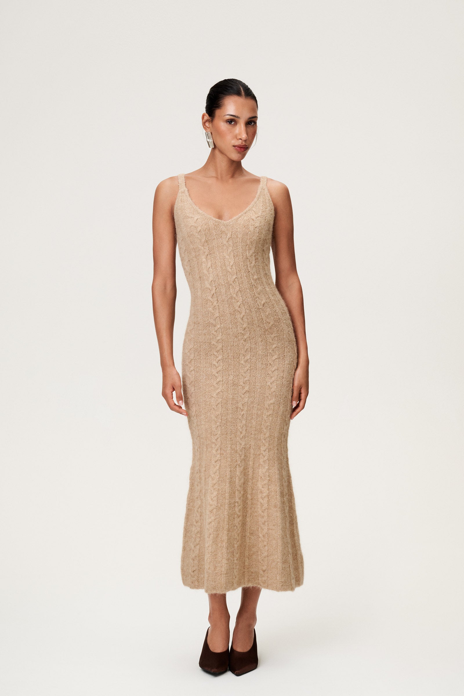 Woman wearing the Merano maxi dress in beige melange, a sleek, figure-flattering style with delicate singlet straps, a deep V-neckline, and an hourglass fit. image