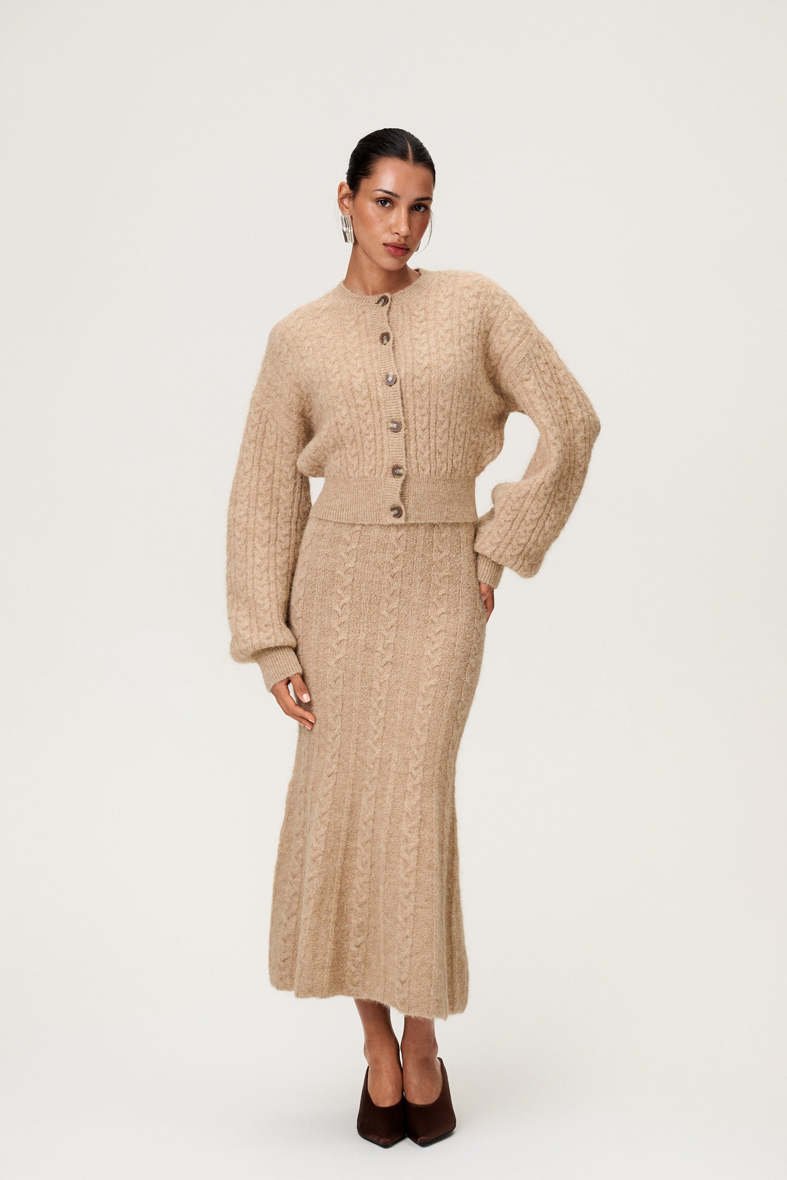 Woman wearing the Merano maxi dress in beige melange with the Merano cardigan in beige melange, a sleek, figure-flattering style with delicate singlet straps, a deep V-neckline, and an hourglass fit. image